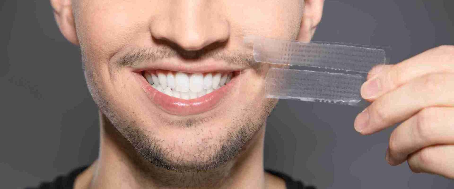 ragazzo utilizza le strisce sbiancanti per denti 